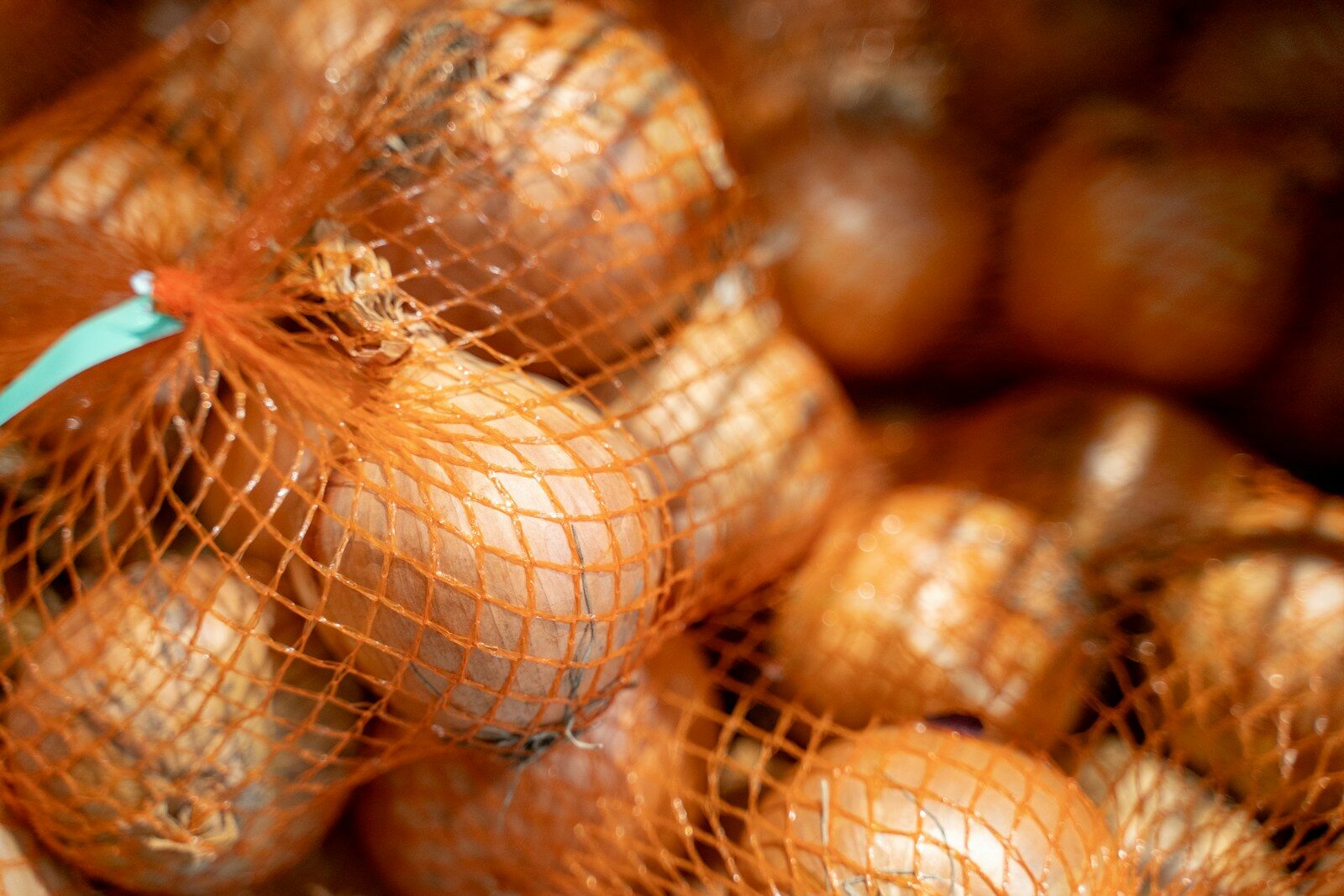 Onions in orange netting bags stacked together